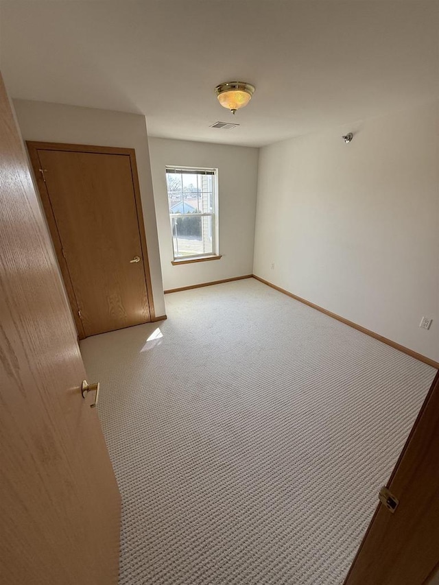 empty room with light carpet, visible vents, and baseboards