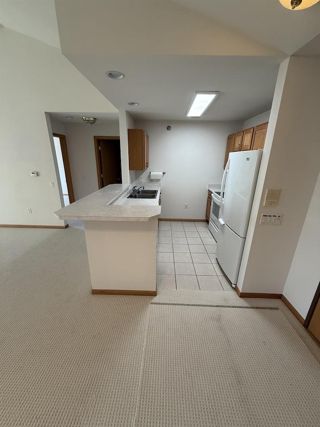 kitchen with baseboards, light countertops, white appliances, a peninsula, and light carpet