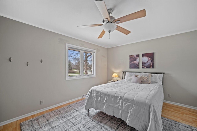 bedroom featuring ceiling fan, baseboards, ornamental molding, and wood finished floors