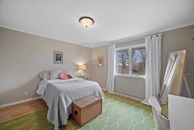 bedroom featuring a baseboard radiator, wood finished floors, crown molding, and baseboards