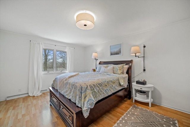 bedroom with a baseboard heating unit, baseboards, light wood-style floors, and ornamental molding