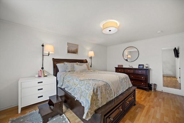 bedroom featuring light wood finished floors, crown molding, and baseboards