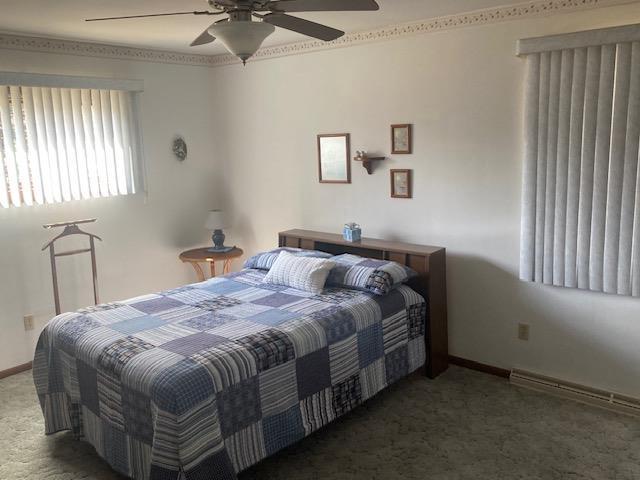 carpeted bedroom with ceiling fan and baseboards