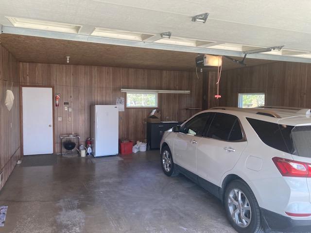 garage featuring wooden walls and freestanding refrigerator