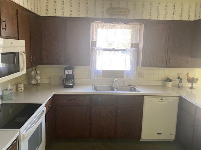kitchen featuring white appliances, light countertops, a sink, and backsplash