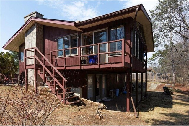 607 Cross Ave, Amery, WI 54001 - rear view of house with a wooden deck, a patio, fence, stairs, and a chimney