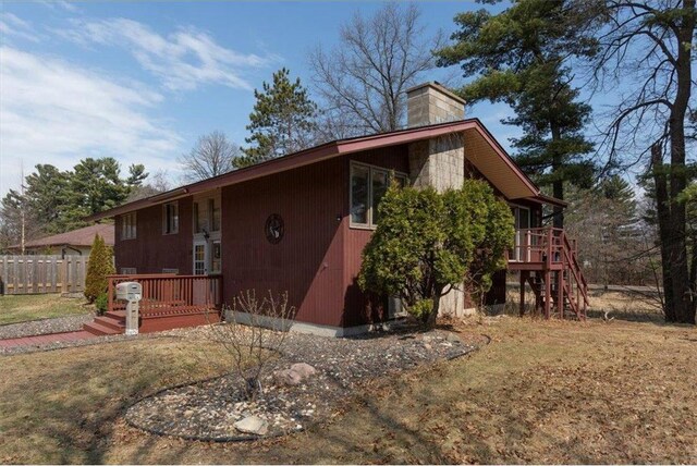 607 Cross Ave, Amery, WI 54001 - view of side of home with fence, a wooden deck, and a chimney
