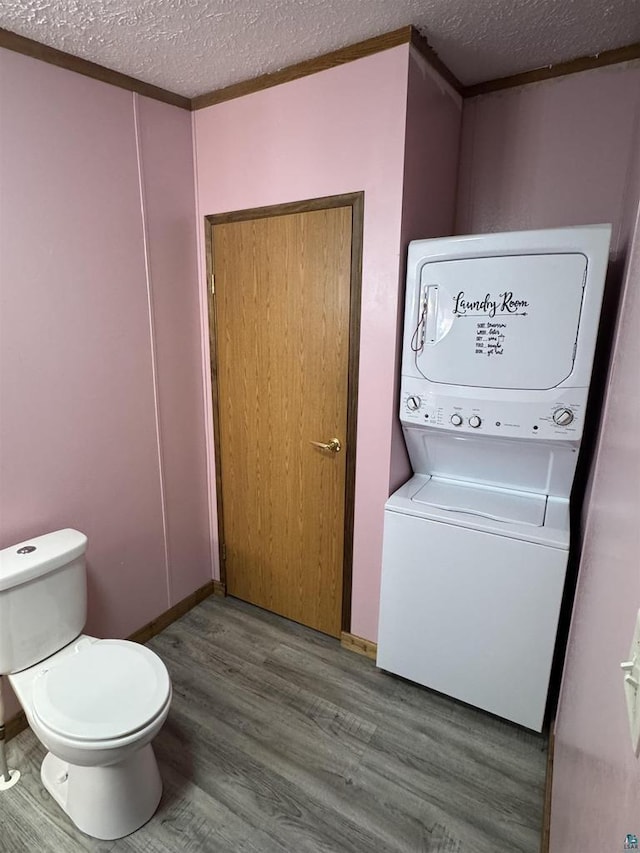 68485 N George St, Iron River, WI 54847 - bathroom featuring stacked washer / drying machine, a textured ceiling, wood finished floors, and toilet