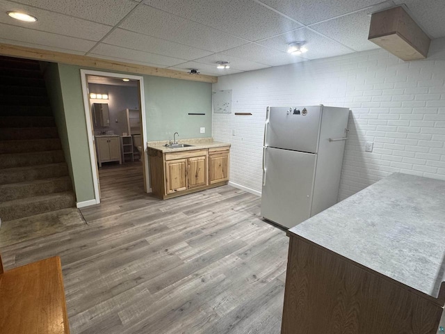 68485 N George St, Iron River, WI 54847 - kitchen featuring freestanding refrigerator, a paneled ceiling, a sink, light wood-style flooring, and light countertops
