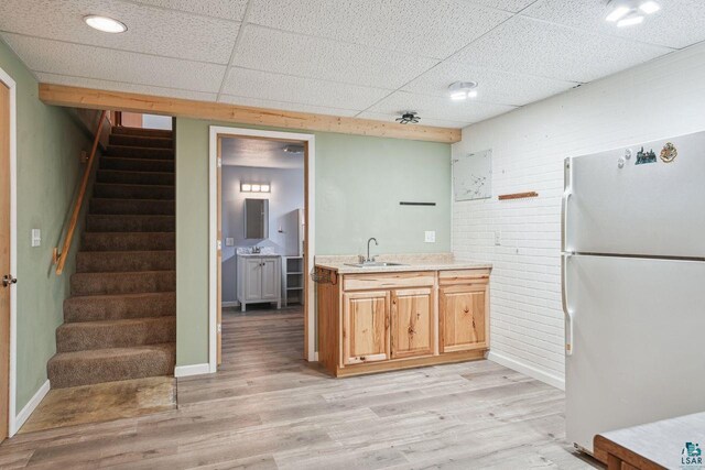 68485 N George St, Iron River, WI 54847 - kitchen featuring freestanding refrigerator, a sink, a paneled ceiling, light countertops, and light wood-style flooring