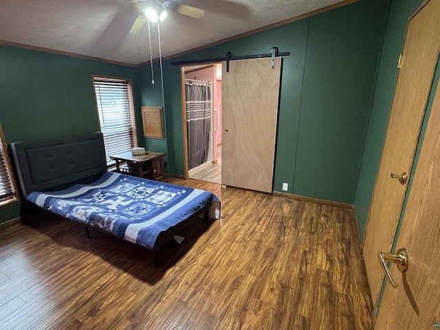 68485 N George St, Iron River, WI 54847 - bedroom with vaulted ceiling, wood finished floors, a textured ceiling, a barn door, and ceiling fan