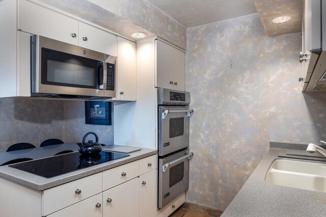 2136 White Swan Dr, Oshkosh, WI 54901 - kitchen with a sink, decorative backsplash, appliances with stainless steel finishes, and white cabinetry
