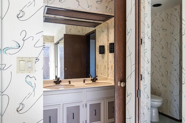 2136 White Swan Dr, Oshkosh, WI 54901 - bathroom with wallpapered walls, double vanity, a sink, and toilet