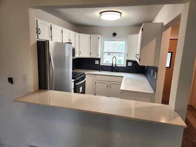 613 Saddle Rdg, Portage, WI 53901 - kitchen featuring freestanding refrigerator, tasteful backsplash, white cabinets, a sink, and black gas range oven