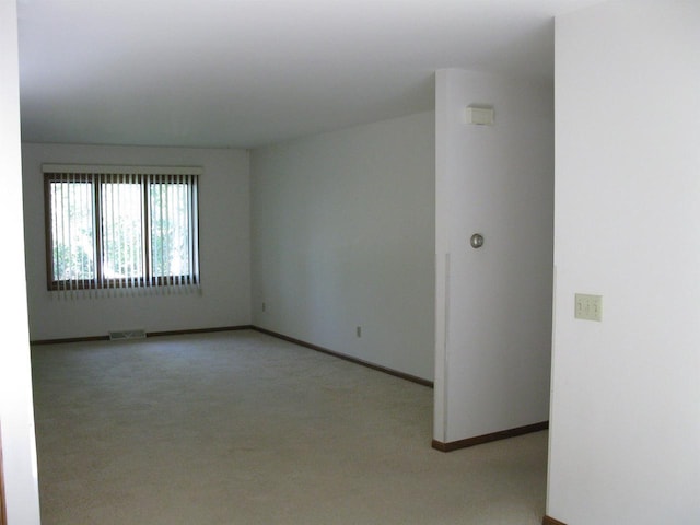empty room with visible vents, baseboards, and light carpet