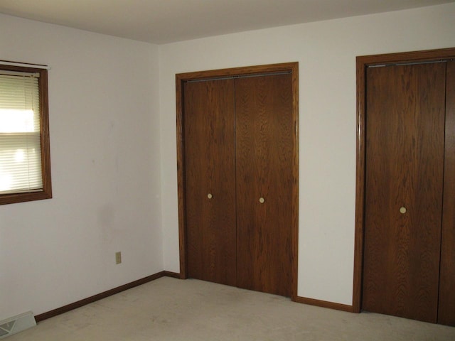 unfurnished bedroom featuring visible vents, light colored carpet, and baseboards