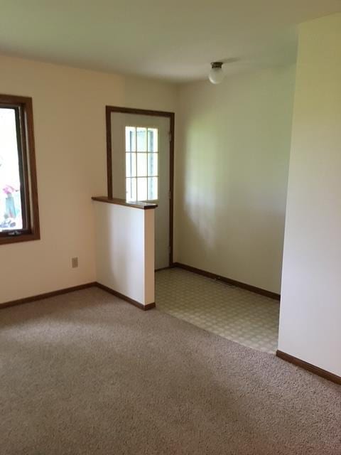 unfurnished room featuring baseboards and light carpet