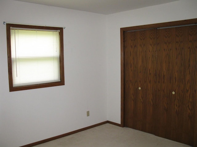 unfurnished bedroom featuring a closet, light colored carpet, and baseboards