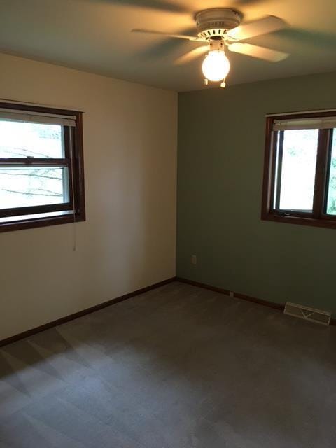 unfurnished room with visible vents, baseboards, a ceiling fan, and carpet floors