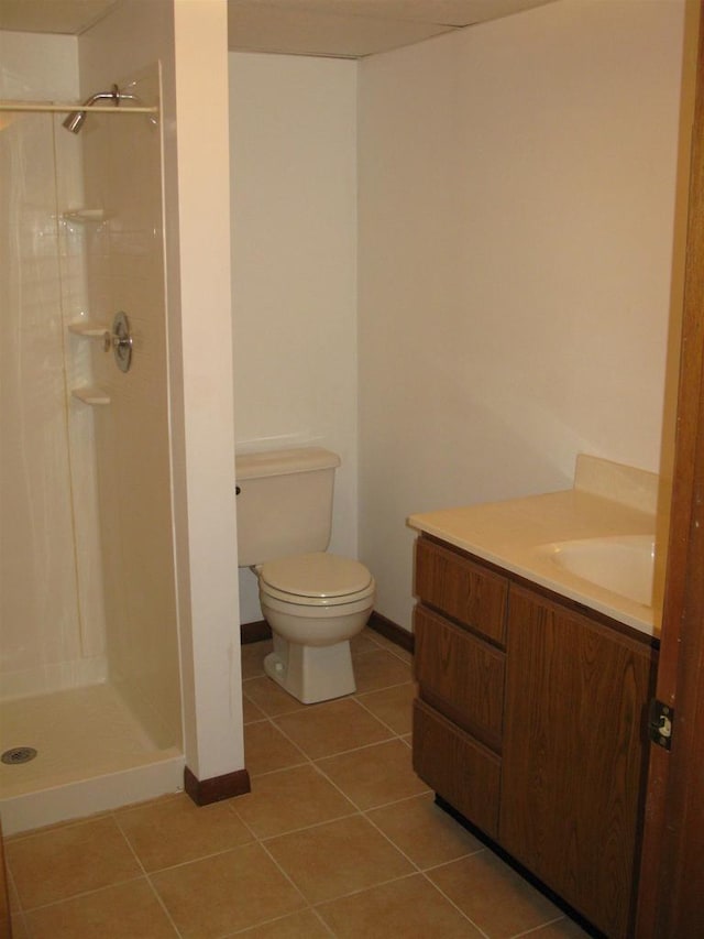full bath with baseboards, toilet, a shower stall, vanity, and tile patterned floors