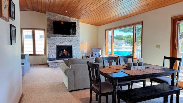 dining area featuring light colored carpet, wooden ceiling, vaulted ceiling, and a stone fireplace