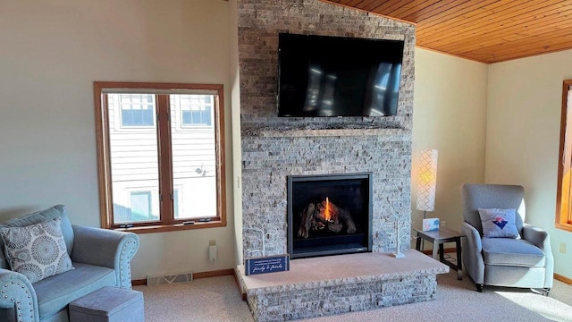 living area with baseboards, visible vents, carpet, wood ceiling, and a fireplace