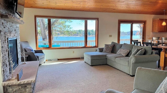 carpeted living area with wood ceiling, baseboards, visible vents, and a fireplace