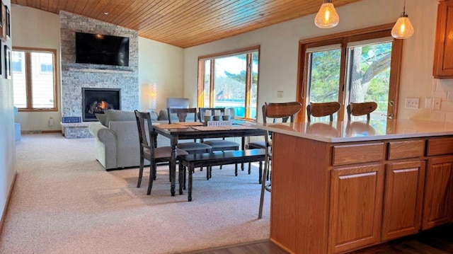 kitchen featuring wooden ceiling, brown cabinets, a stone fireplace, and plenty of natural light