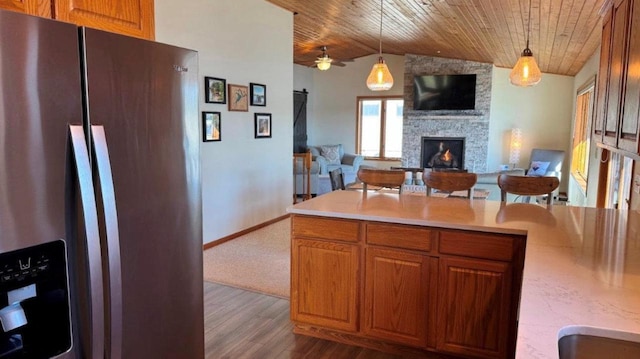 kitchen with light countertops, dark wood-type flooring, decorative light fixtures, wood ceiling, and stainless steel fridge