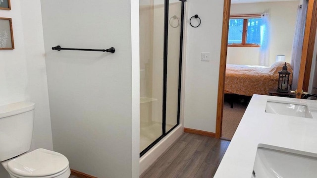 ensuite bathroom with a stall shower, wood finished floors, connected bathroom, and toilet