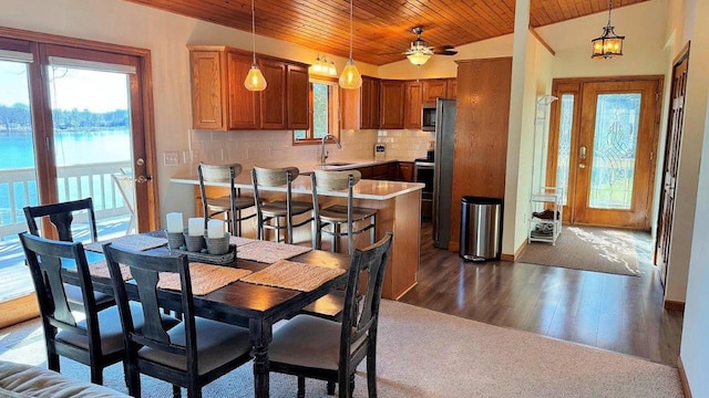 dining area featuring a water view, wood ceiling, ceiling fan, dark wood finished floors, and lofted ceiling
