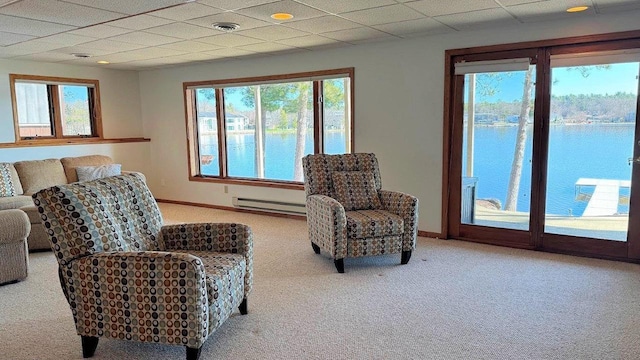 sitting room with baseboard heating, a water view, carpet floors, baseboards, and visible vents