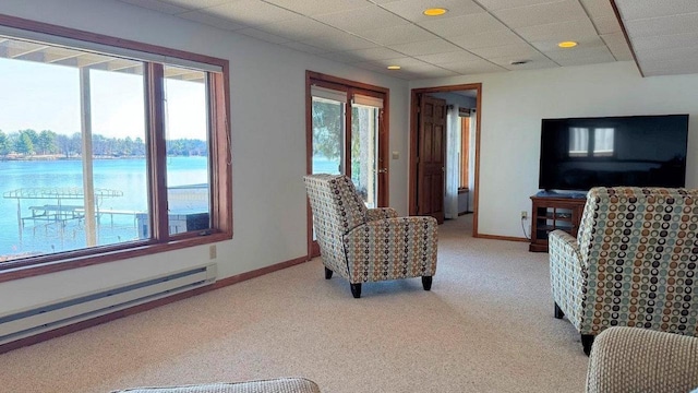 living area with a baseboard heating unit, light colored carpet, and a healthy amount of sunlight