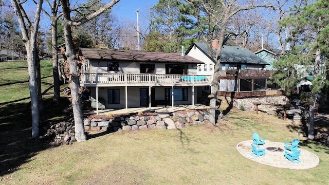 back of property with a fire pit, a yard, and a wooden deck