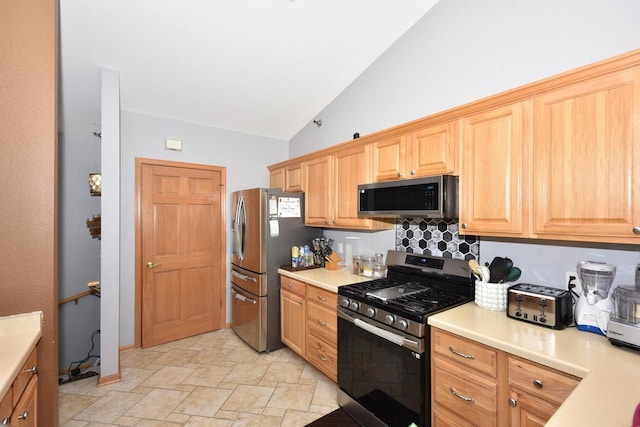 kitchen featuring tasteful backsplash, light countertops, appliances with stainless steel finishes, and stone finish flooring