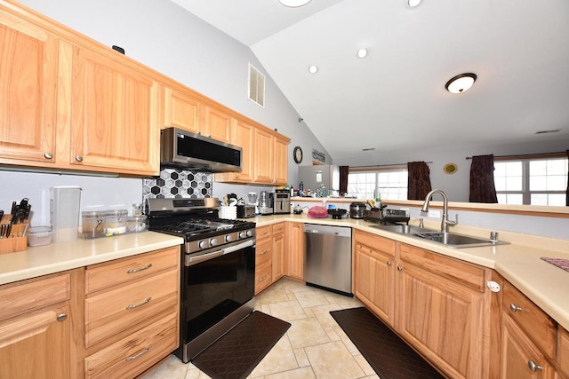 kitchen with light brown cabinets, visible vents, lofted ceiling, stainless steel appliances, and a sink