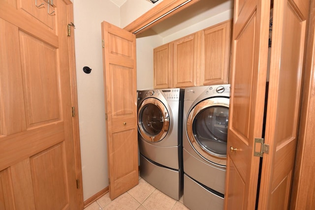 laundry room with light tile patterned floors, washing machine and clothes dryer, and cabinet space