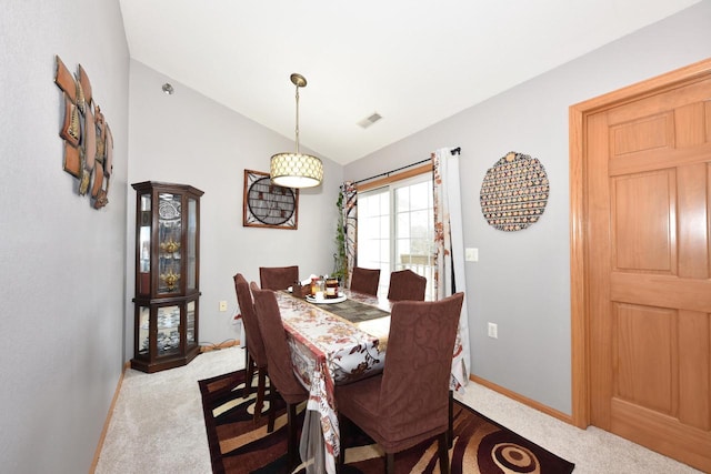 carpeted dining room with baseboards, lofted ceiling, and visible vents