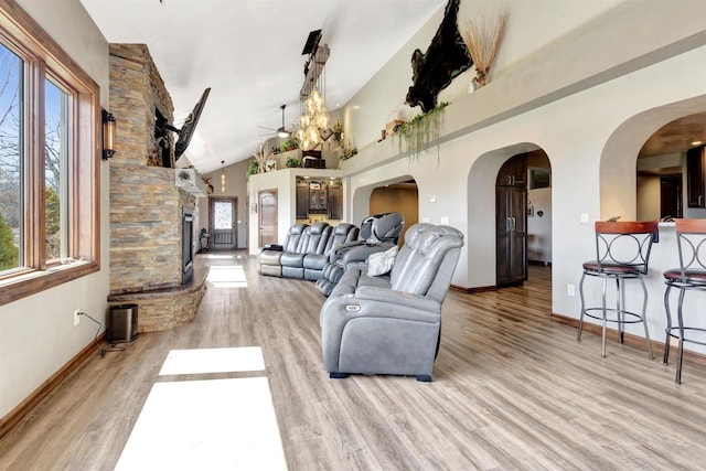 1545 County Rd I, Oshkosh, WI 54902 - living room with baseboards, a stone fireplace, a ceiling fan, arched walkways, and wood finished floors