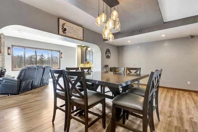 1545 County Rd I, Oshkosh, WI 54902 - dining space featuring baseboards, light wood-type flooring, arched walkways, and a notable chandelier