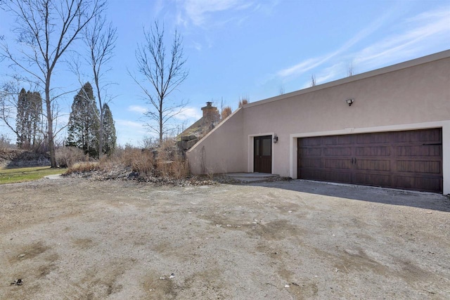 1545 County Rd I, Oshkosh, WI 54902 - view of side of property featuring stucco siding, a chimney, and an attached garage