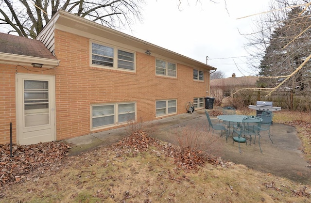 rear view of property featuring a patio, brick siding, and fence