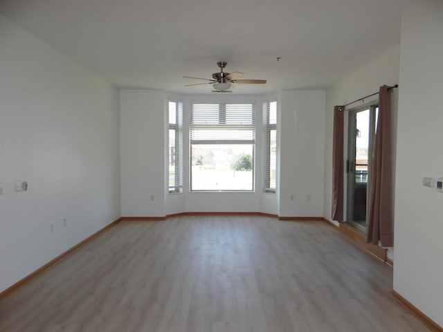 spare room featuring light wood-type flooring, baseboards, and ceiling fan