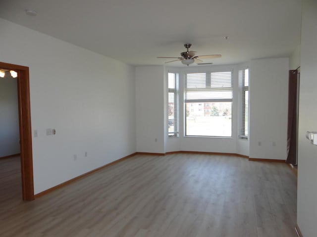 empty room with light wood finished floors, baseboards, and ceiling fan