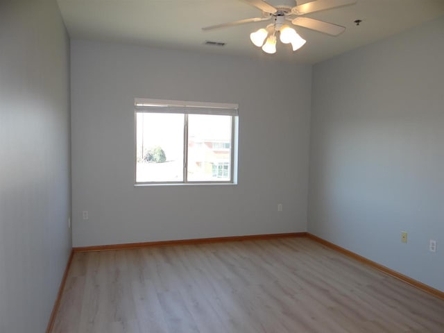 empty room with light wood-type flooring, ceiling fan, baseboards, and visible vents