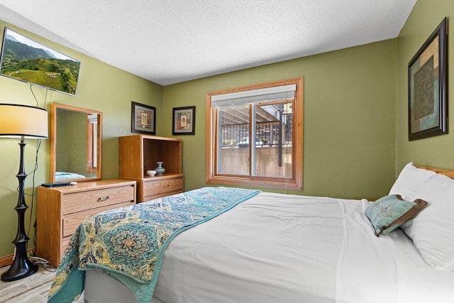 bedroom with baseboards, wood finished floors, and a textured ceiling