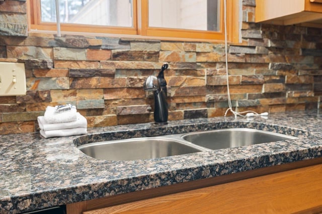 details featuring a sink, backsplash, and dark stone countertops
