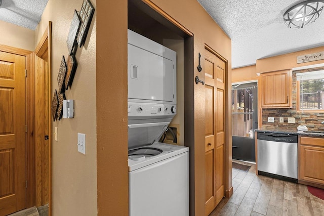 interior space with light wood-style flooring, a textured ceiling, stacked washer and dryer, and a sink