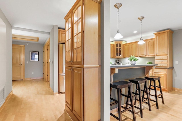 123 W Washington Ave Unit 306, Madison, WI 53703 - kitchen with light wood-style flooring, a kitchen breakfast bar, glass insert cabinets, freestanding refrigerator, and baseboards