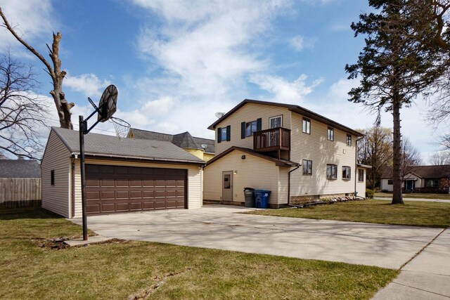 1001 Wisconsin Ave, North Fond Du Lac, WI 54937 - view of front facade with a detached garage, a front yard, fence, and a balcony